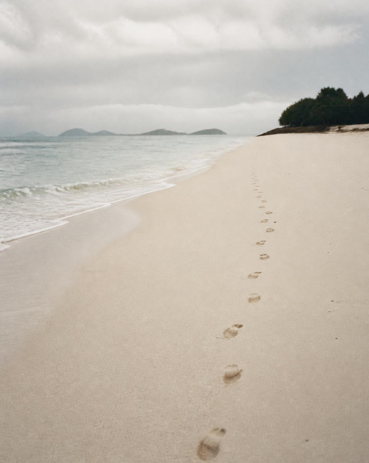 Empty pale sand beach with a single trail of footprints